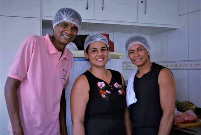 Equipe do buffet com touca na cozinha, sorrindo para a camera