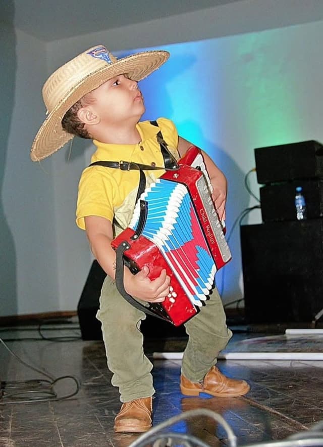 Menino de chapéu de palha com sanfona no palco